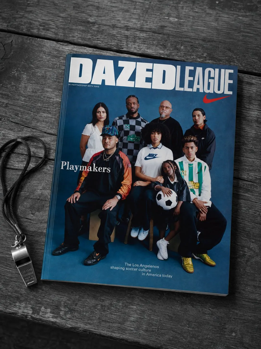 The blue Dazed League magazine showing eight football playmakers on its cover, placed on a monochrome wooden floor