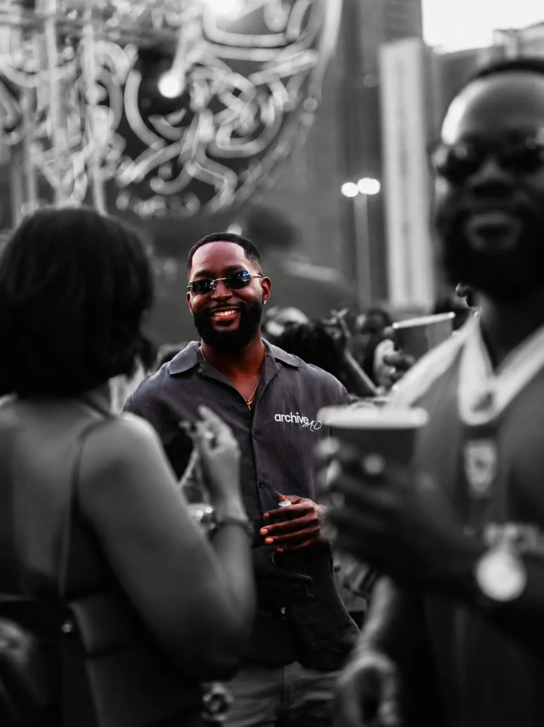 A smiling man in an Archive shirt at a Dubai festival, picked out in colour against a monochrome crowd