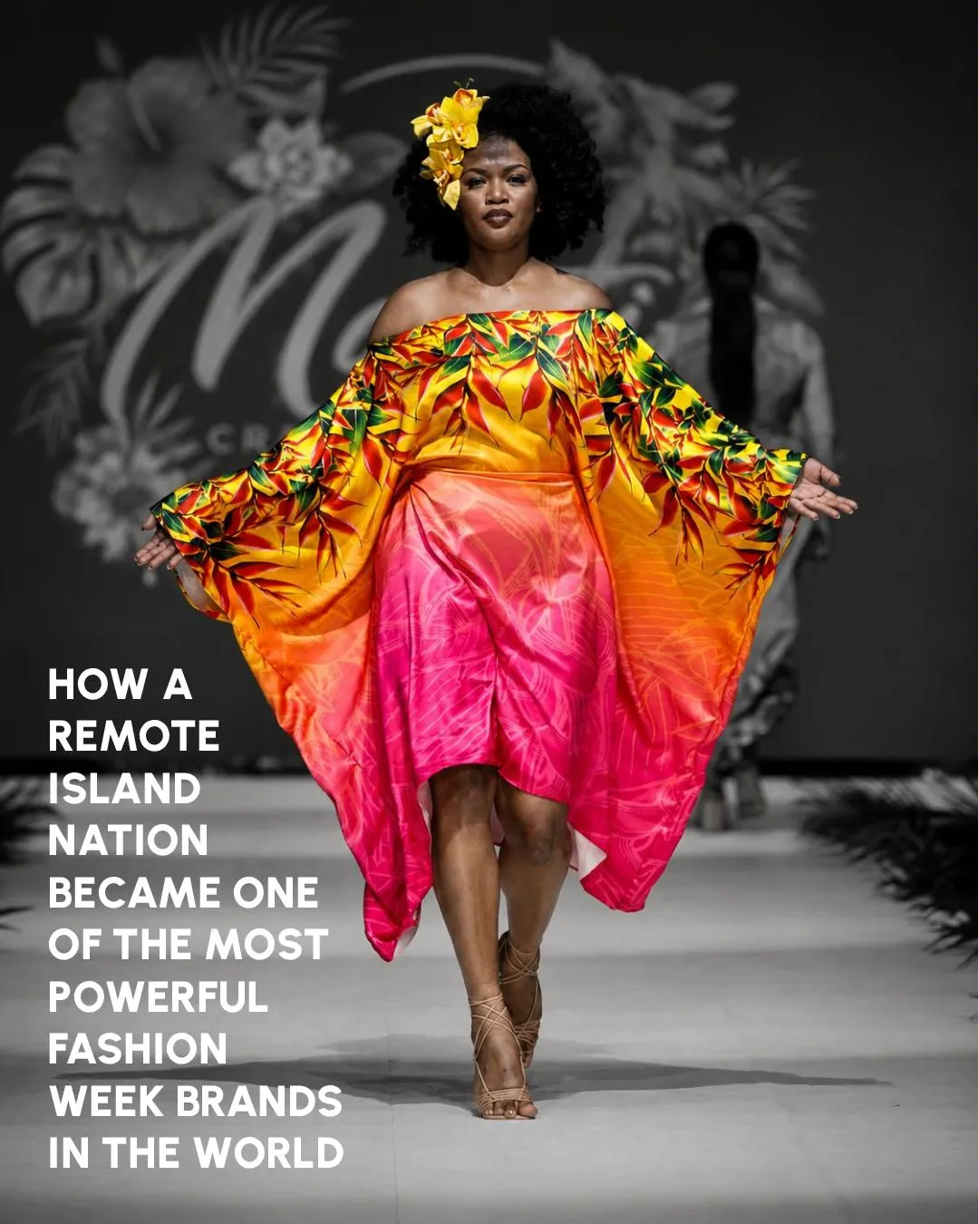 A model in a sunset-coloured dress and yellow orchids walking a monochrome runway at Fiji Fashion Week