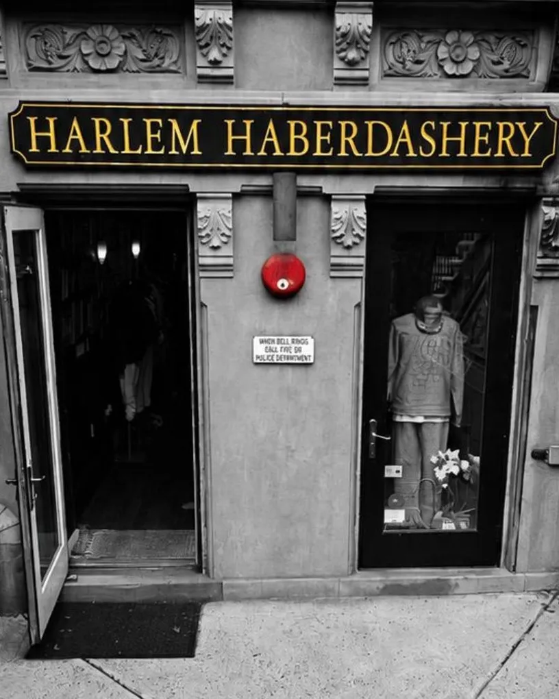The Harlem Haberdashery storefront in monochrome, a red fire bell the only colour above the door