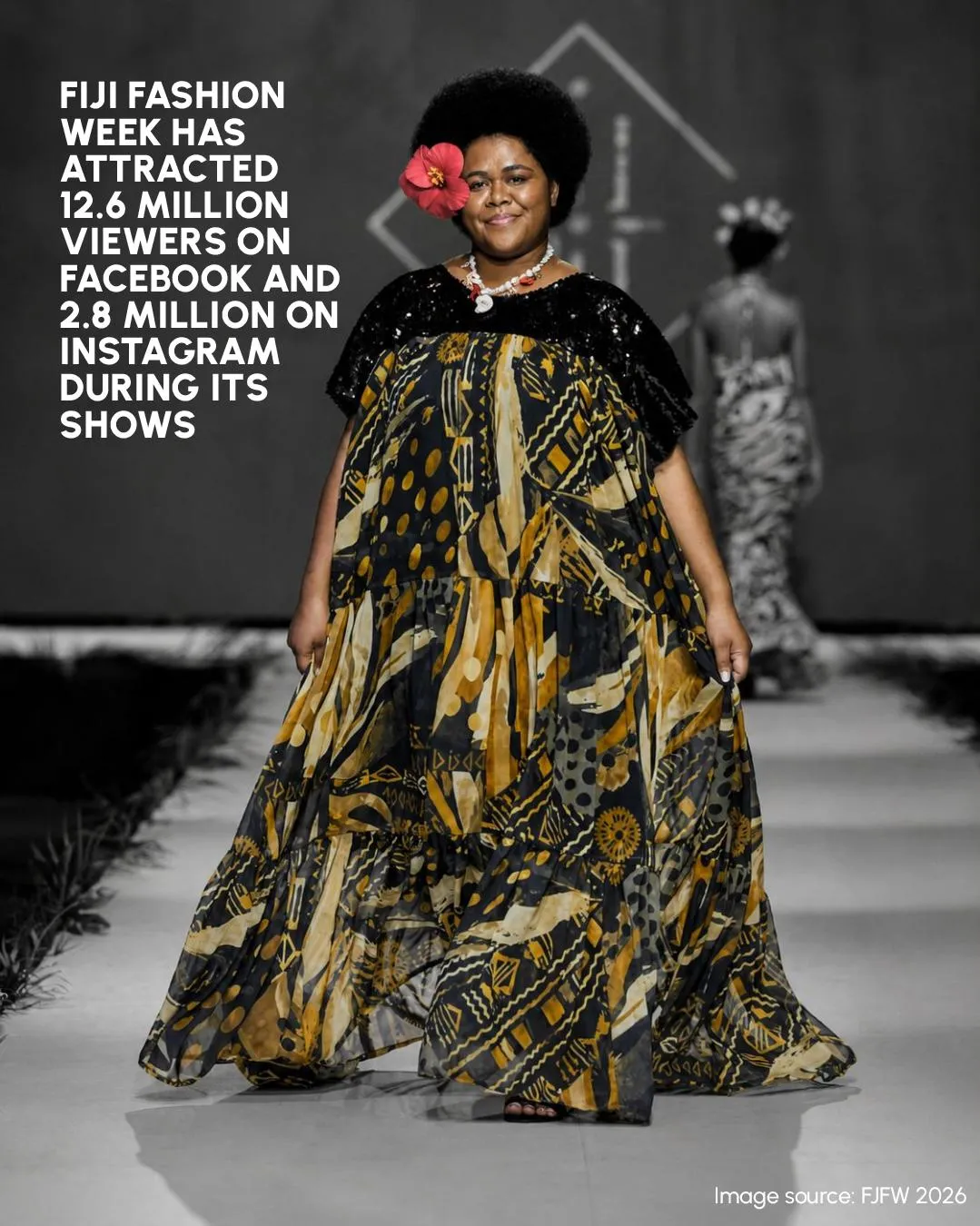 A model in a black and gold gown with a red hibiscus behind her ear
