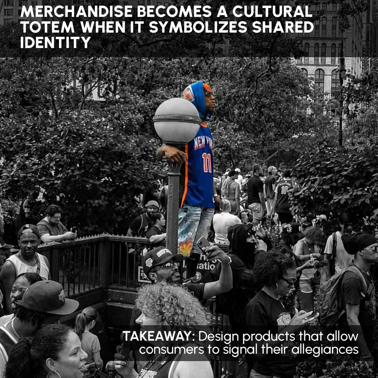 A fan in a blue New York jersey standing on a lamppost above the crowd